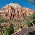 Captivating view of Zion National Park's towering red cliffs along a winding road under a clear blue sky.