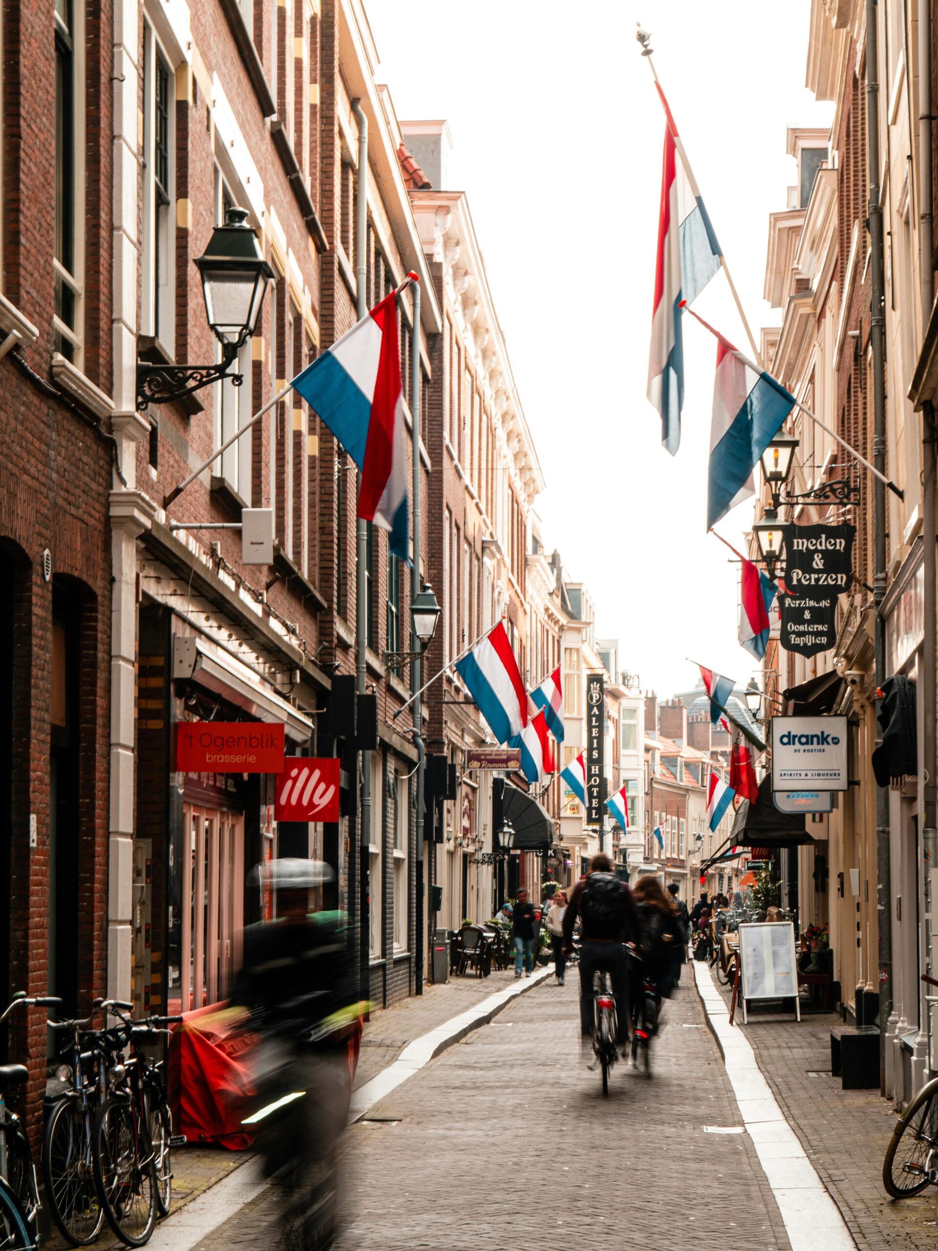 Vibrant urban scene in The Hague with bicycles, Dutch flags, and historic buildings.